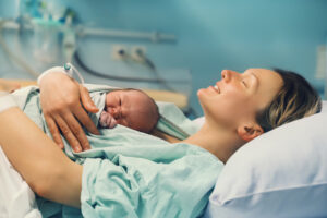 A woman holding her newborn baby in the hospital and smiling